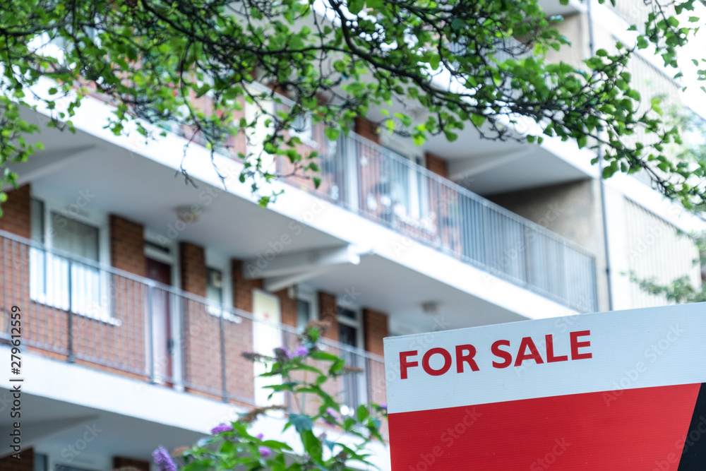 Estate agent  'FOR SALE' sign on street of urban houses