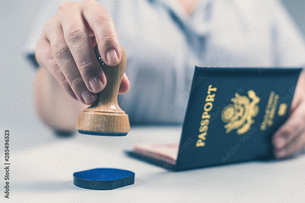 Immigration and passport control at the airport. woman border control officer puts a stamp in the US passport of american citizen. Concept